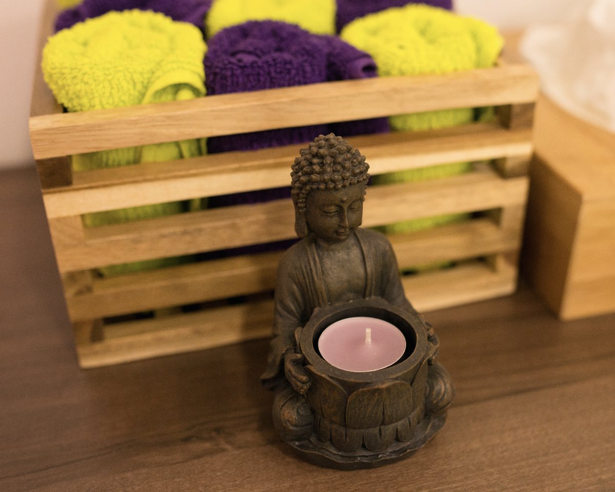 Buddha-Figur mit Kerze und Handtüchern im Behandlungsraum