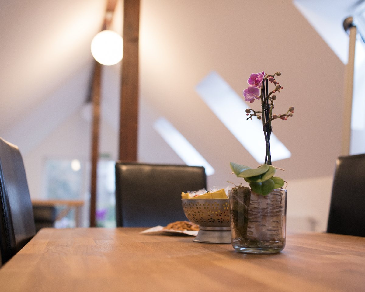 Heller Wohnraum unter dem Dach mit Holztisch und Orchidee